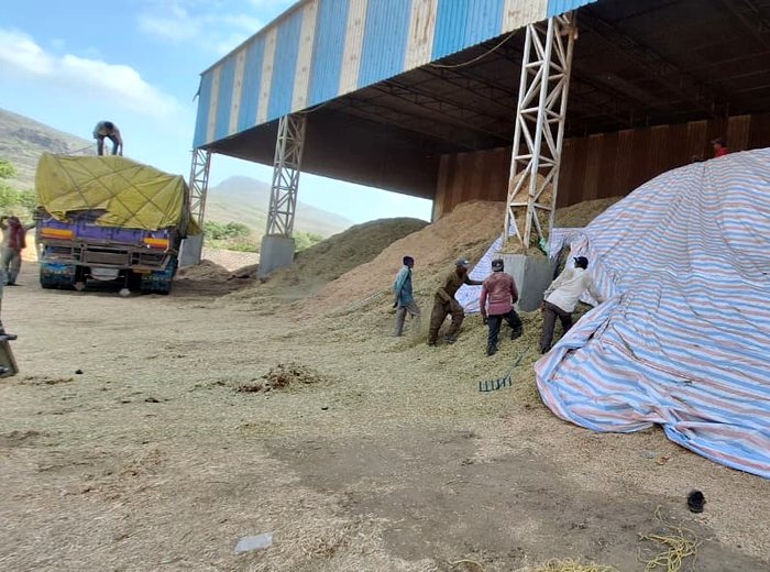 Workers unloading raw agro residue from a truck at the Junagadh plant